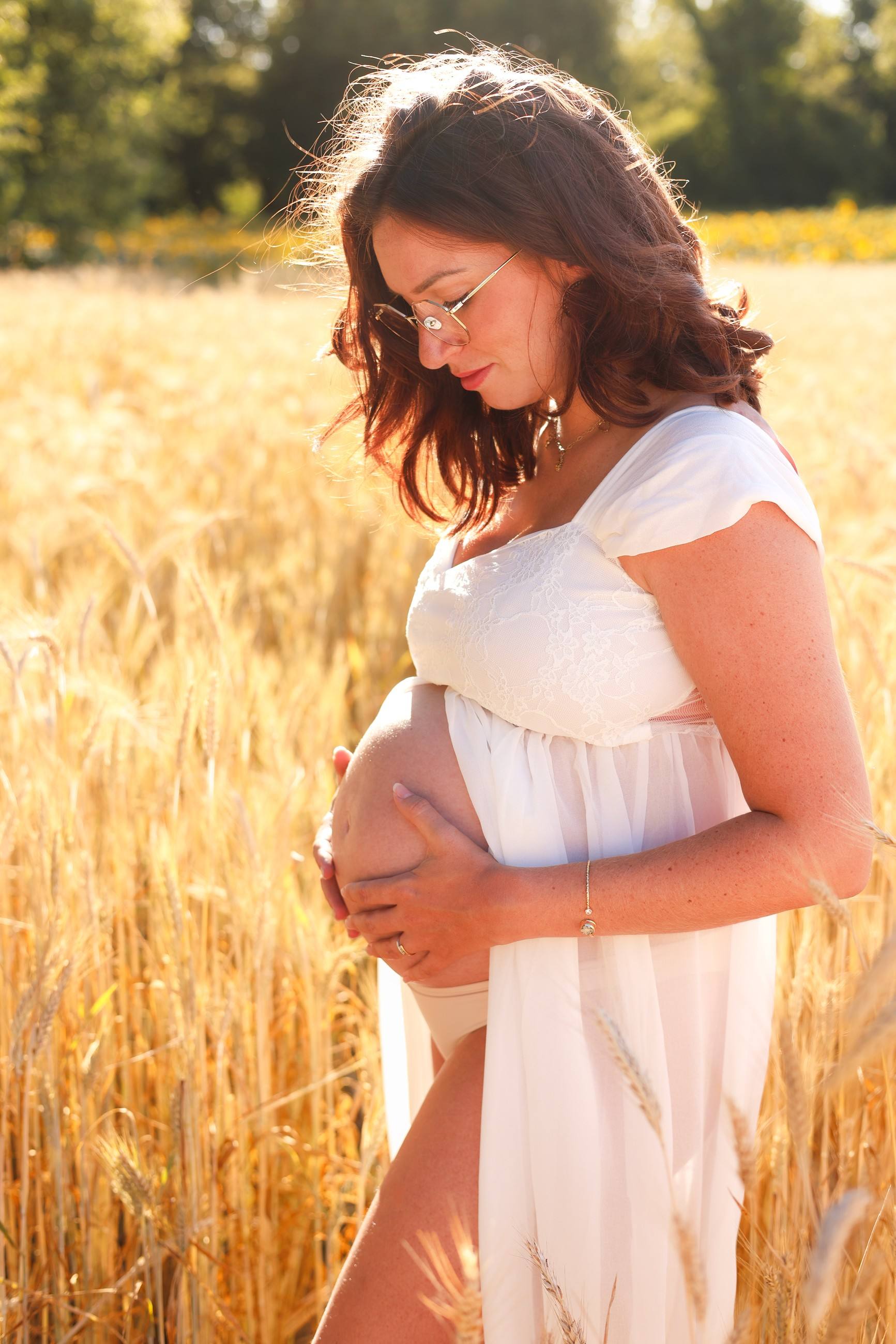 Femme enceinte dans un champ de blé à la lumière dorée
